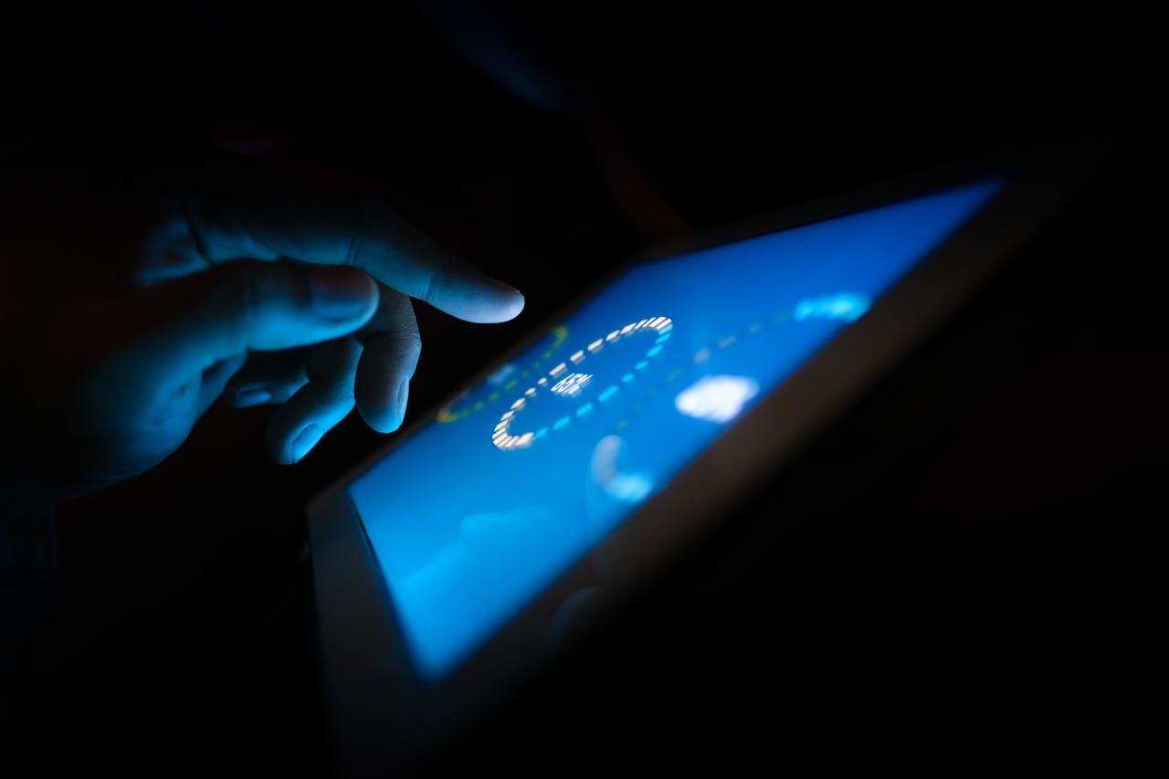 who-we-are Close-up of a hand interacting with a glowing touchscreen in a dark setting, highlighting technology use.